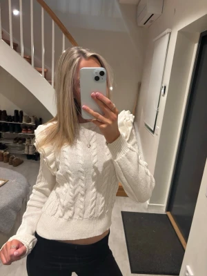 Vit kabelstickad tröja från ONLY - Säljer en vit kabelstickad tröja från ONLY med puffärmar och ribbade muddar. Tröjan har en croppad passform och är tillverkad i mjukt material. Perfekt för dig som gillar trendiga detaljer och vill ha en stilren look.