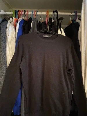 Svart stickad tröja från Oscar Jacobson - Klassisk svart stickad tröja från Oscar Jacobson med rund halsringning och långa ärmar. Tröjan har en enkel och stilren design som passar till det mesta. Materialet ser ut att vara mjukt och tunt, perfekt för lager på lager.