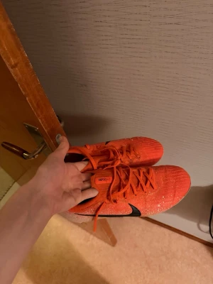 Nike Mercurial vapor 12 - Säljer ett par Nike Mercurial fotbollsskor i rött med svarta detaljer och vita hälar. Skorna har snörning och är tillverkade i ett lätt syntetmaterial för bra bollkontroll och grepp på planen. Perfekta för dig som vill ha snabbhet och stil på fotbollsplanen.