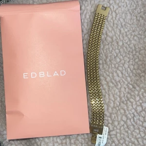 Guldigt armband från Edblad - Snyggt armband i guldton från Edblad i storlek small med bred, flätad kedja och stilren låsdetalj. Armbandet har en modern och trendig look som passar perfekt till din outfit. Levereras med originalförpackning. 