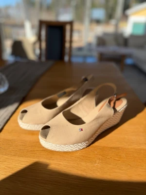 Tommy Hilfiger - Beige kilklackar  - Beige kilklack med öppen tå från Tommy Hilfiger. Använd 2 tillfällen.