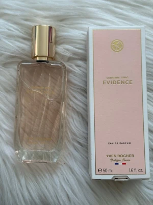 Comme une Evidence parfym Yves Rocher - Comme une Evidence Eau de Parfum från Yves Rocher. Flaskan är rektangulär i genomskinligt glas med ljusrosa doft och guldfärgad kork. Medföljer gör en ljusrosa och vit kartong med guldiga detaljer. Innehåller 50 ml.