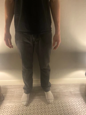 Svarta raka jeans från dressman - Säljer ett par svarta jeans med rak passform och klassisk femficksdesign. Jeansen har normal midja och är tillverkade i ett denimtyg som känns mjukt men ändå slitstarkt. Perfekta för dig som gillar en enkel och stilren look.