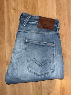 Replay jeans  - Ljusblåa Replay jeans med slitningar och hål med en slim passform. Midja 38cm, längd 110cm. Obs jeansens tyg baktill har blivit något förtunnat - se bild. JAG SKICKAR EJ FLER BILDER NÄR JAG BÄR JEANSEN! för bättre inblick i passformen rekommenderar jag att googla på modellnamnet. För storleksguide kolla måtten noggrant då jeansen alltid kan vara uppsydda heller krympta och jag ej tar emot returer :) 1,80