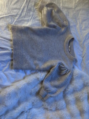 Grå stickad tröja med puffärm - Mysig grå stickad tröja med trendiga puffärmar och ribbade muddar vid ärmslut och nederkant. Rund halsringning och rak passform. Perfekt för lager-på-lager och en stilren look.