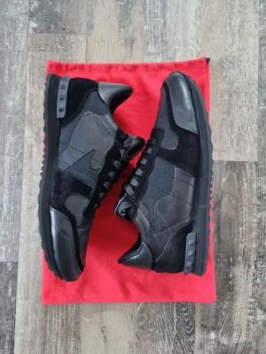 Valentino rockrunners  - Snygga svarta sneakers🙌🙌 från Valentino med coola camo-detaljer och mix av mocka och läder👌👌. Skorna har svarta snören, diskret logga på plösen🤑🤑 och en unik sula med nitar baktill🧠🧠. Perfekta för dig som gillar streetstyle och exklusiva märken. Nya pris 8200kr‼️‼️