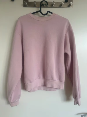 Ljusrosa sweatshirt med rund hals - En basic ljusrosa sweatshirt med rund halsringning och ribbade muddar vid ärmslut och nederkant. Perfekt för en avslappnad och stilren look. Tillverkad i mjukt material som känns skönt mot huden. 