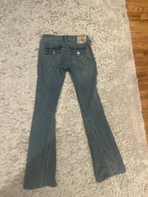Blå bootcut jeans från True Religion - Säljer nu dessa snygga blå bootcut jeans från True Religion som är perfekta till våren. Köptes för 1300 kronor och har aldrig använts. Modell och storlek syns på sista bilden!