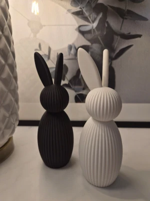 Dekorativa påskharar i svart och vitt - Två stilrena dekorationsfigurer i form av påskharar, en svart och en vit. Båda har räfflad yta och långsmala öron. Perfekta som dekoration till påsk. 