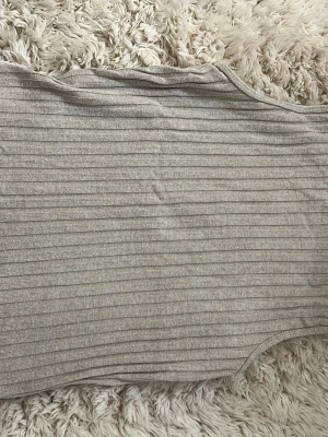 Beige ribbad linnetopp Gina Tricot - Snygg beige ribbad linnetopp från Gina Tricot. Toppen är ärmlös och har en tight passform med rund halsringning. 