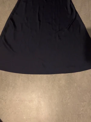 Mörkblå långkjol i mjukt tyg - En stilren mörkblå långkjol med lätt utsvängd passform. Kjolen är enkel och enfärgad, vilket gör den lätt att matcha med olika toppar. Tillverkad i ett mjukt och följsamt material som ger en snygg siluett.