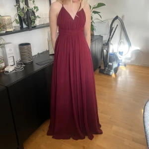Vinröd balklänning med öppen rygg - Säljer min balklänning från förra året i storlek 30 vilket motsvarar XXS/XS men den är fof lång. Den är från Ivory Field och har bara använts en gång. Jag har sytt upp v-ringningen så att den är mindre v-ringad vilket syns på fjärde bilden, men den är handsydd och borde gå att sprätta upp utan att det blir märken. Kan prisförhandla! Nypris: 1899kr
