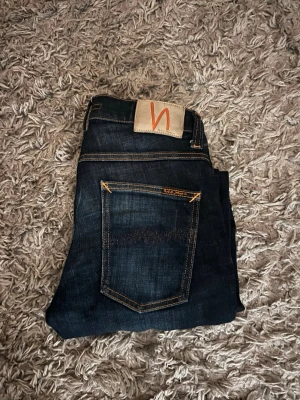 Nudie jeans - Mörkblå jeans från Nudie. De är i nyskick och midjan är 28 och längden är 32.