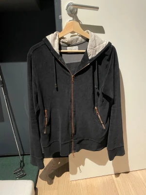 Limitato Hoodie  - Cool svart hoodie från limitato med  bronsfärgade dragkedjor. Baksidan har ett stort svartvitt tryck med texten 'Float like a butterfly, sting like a bee'. I mjukt sammets tyg. Ena toppen av snörerna är av.