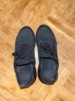 Svarta Nike Air Max 270 sneakers - Säljer ett par helsvarta Nike Air Max 270 sneakers i storlek 38 med mesh-överdel Skorna har snörning och diskreta Nike-loggor på sidorna. Perfekta för dig som gillar sportig och clean stil. storlek 38!