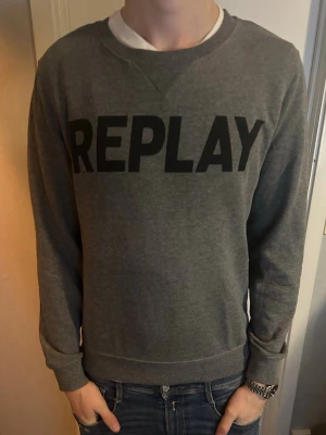 Grå sweatshirt från Replay - Snygg grå sweatshirt från Replay med stor svart logga över bröstet. Gott skick. Strlk M. Pris går att diskutera.