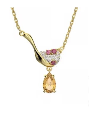 Guldhalsband med färgade stenar Swarovski - Unikt halsband i guldton från Swarovski med droppformad gul sten och små vita och rosa stenar i ett elegant mönster. Kedjan är tunn och smycket har en modern, lyxig känsla som sticker ut.