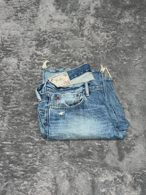 Polo Ralph Lauren Distressed Denim Shorts -   denimshorts från Polo Ralph Lauren. De har en snygg tvätt med naturligt slitna detaljer och råa, fransiga benslut (cut-offs). Toppskick 