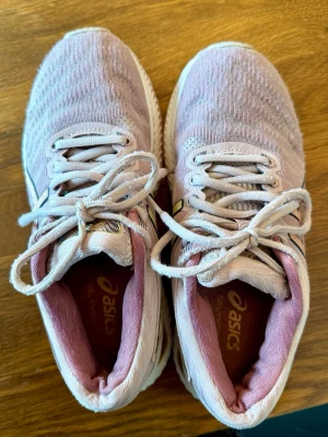Ljusrosa Asics sneakers med mesh - Säljer ett par ljusrosa Asics sneakers/löpskor med ovandel i ventilerande mesh och vita snören. Skorna har en klassisk låg siluett och bekväm innersula. Perfekta för dig som gillar sportig stil och vill ha något lätt på foten.