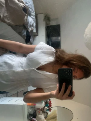 Zara Vit blus med v-ringning  - Säljer en snygg vit blus med v-ringning och korta ärmar. Blusen har en figurnära passform och klassisk krage, perfekt för att skapa en stilren look. Materialet känns lätt och luftigt, vilket gör den bekväm att bära hela dagen.