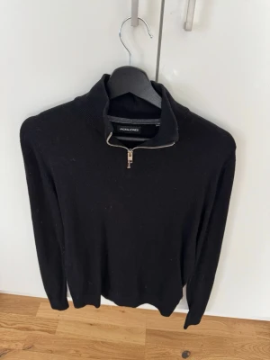 Svart stickad tröja med halvzip - Snygg svart stickad tröja från Jack & Jones med halvzip. Enkel och stilren design som funkar till det mesta.