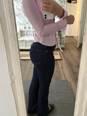 Mörkblå bootcut jeans - Snygga mörkblå bootcut jeans med klassiska fickor och kontrastsömmar. Jeansen har hög midja och sitter tajt över höfterna innan de släpper ut vid benen. Perfekta för en trendig och avslappnad look.
