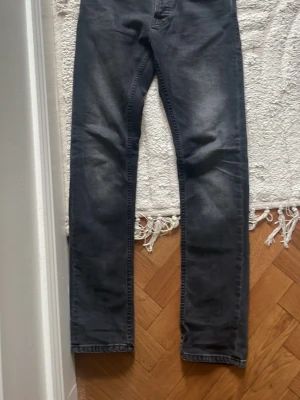 Nudie grim tim  - Riktigt snygga Nudie jeans i mörk grå färg. Storlek 28 32 i modellen ”grim tim”