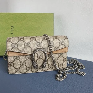  Supreme handväska -  handväska i beige canvas med Supreme-mönster och detaljer i ljusbrunt läder. Väskan har en silverfärgad kedjerem och ett ikoniskt spänne med ormdetaljer framtill. Perfekt för dig som gillar lyxiga accessoarer. Kommer med dustbag och lådan 