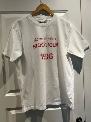 Acne Studios Stockholm 1996 T-shirt - Tjena, säljer denna skitsnygga acne studios T-shirten från deras Stockholm 1996 modell med ljusrosa tryck, på bilden ser den mörkröd ut men de e någon kamera setting elr nåt. Enligt mig den snyggaste modellen. Tröjan är i storlek S och passar perfekt med allt och även året runt. Skriv gärna vid intresse! Köpt här på Plick o säljer vidare.