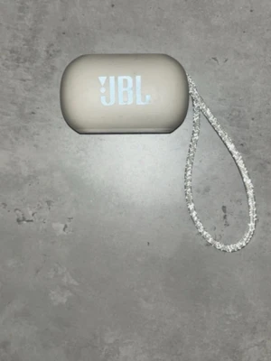 JBL trådlösa in-ear hörlurar grå - Säljer ett par stilrena trådlösa in-ear hörlurar från JBL i grått. Hörlurarna kommer med ett matchande laddningsetui och en snygg rem för enkel transport. Perfekta för musik, poddar eller samtal på språng.