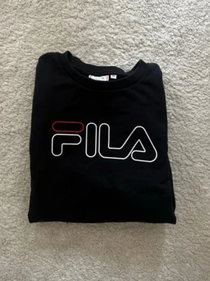 Svart sweatshirt från FILA - Snygg svart sweatshirt från FILA med logga över bröstet. Sällan använd så i bra skick. Storlek M men passar även S