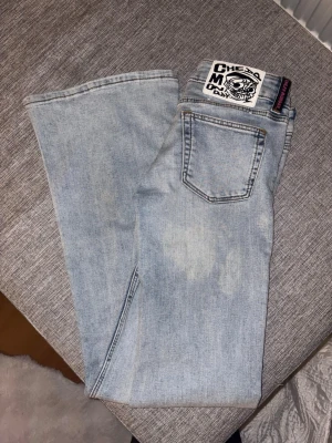 Ljusblå bootcut jeans Cheap Monday - Säljer ett par ljusblå bootcut jeans från Cheap Monday med klassisk femficksdesign och coolt patch på bakfickan. Jeansen har slitningar framtill och är tillverkade i bomull. Perfekt för dig som gillar en avslappnad och trendig look.