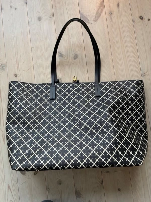 Malene Birger väska Abi Tore k mycket bra skick. - Malene Birger shoppingväska i svart och beige med grafiskt rutmönster. Väskan har långa svarta handtag och stängs med ett guldfärgat spänne. Insidan är rymlig och ljus, perfekt för att bära med sig allt man behöver. Inga fläckar. Modell Abu rote botten 38x17cm väskan h 33 b 56. Kostar 3200kr som ny.