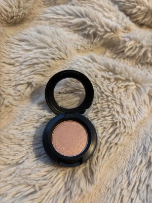 MAC All That Glitters ögonskugga - Säljer en MAC All That Glitters ögonskugga i en skimrande champagne-nyans. Kommer i en rund svart dosa med genomskinligt lock. Perfekt för att skapa en glowy look med sammetslen finish.
