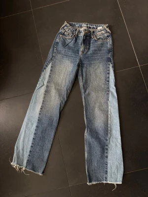 Blå jeans med detaljer på sidorna - Säljer ett par blå raka jeans i storlek xs med detaljer på sidorna.  