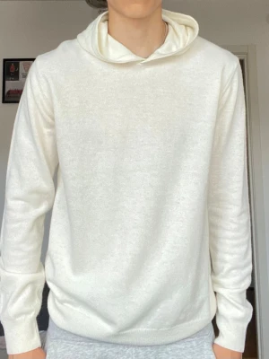 Vit hoodie från Oscar Jacobson - Säljer en stilren vit hoodie från Oscar Jacobson. Hoodien har en mjuk känsla, klassisk huva och ribbade muddar vid ärmslut och nederkant. Tillverkad i Italien och passar perfekt för dig som gillar minimalistisk och clean stil. 