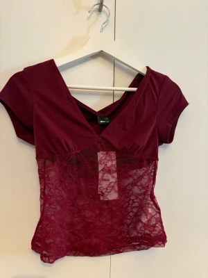 Vinröd spetsblus med v-ringning - Topp ifrån Gina. Bara provad och aldrig använd. Prislappen sitter kvar. Nypris 260kr💞
