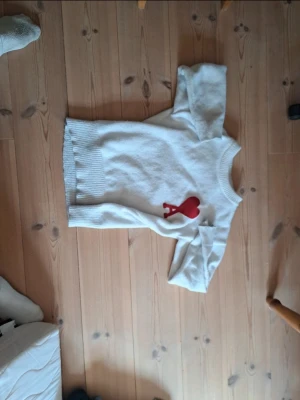Ami paris Vit Stickad Tröja - Vit stickad tröja med rund hals och ribbade muddar. På bröstet finns ett stort rött hjärta med bokstaven A, vilket ger en unik och trendig look. Perfekt för dig som gillar stilrena plagg med en twist.