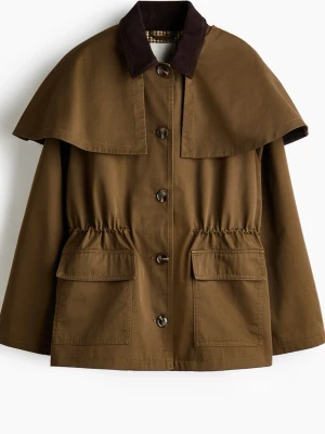 Trenchcoat  - Militärgrön”/brun jacka från H&M. Har en resår i midjan vilket gör att den får en figursydd form, men går även att inte dra åt vilket gör den mer rak och avslappnad. Den har även en cape som är avtagbar med hjälp av knappar bak. ☀️ Rutigt mönster på insidan, se sista bild. Använd 1-2 gånger. Nypris 649kr