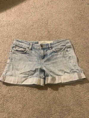 Ljusblå jeansshorts - Säljer ett par ljusblå jeansshorts med klassisk femficksdesign, uppvikta benslut och knapp- samt dragkedjestängning. kan vikas upp om du vill ha kortare! Perfekta till sommaren💞