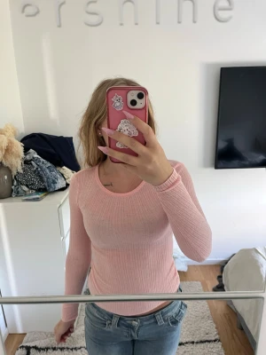 Ljusrosa ribbad långärmad topp - Supersöt ljusrosa långärmad topp med ribbad struktur och rund hals. Sitter tight och är perfekt att styla med jeans eller kjol. Mjuk och stretchig, passar dig som gillar en enkel men ändå trendig look.genomskinlig 