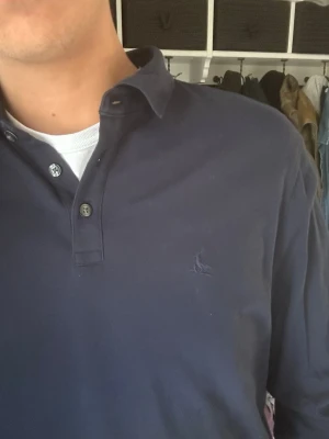 Charles Tyrwhitt långärmad Piké - Mörkblå långärmad piké från Charles Tyrwhitt med klassisk krage och knappslå. Skjortan har en diskret broderad logga på bröstet och är gjord i mjuk bomull. Perfekt till jeans för en clean och stilren look.