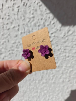 Handgjorda örhängen - lila glittriga blommor - Gulliga små mörklila blommor med glitter i färgen. Sitter på stift av rostfritt stål. Gjorda för hand av mig i polymerlera. 