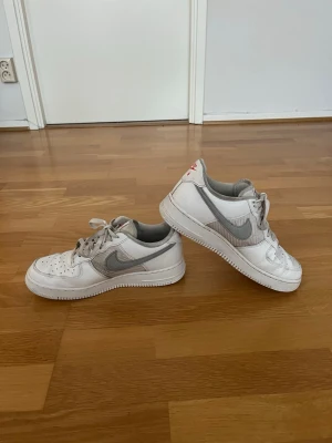 Nike Air Force 1 Low – Storlek 42 - Säljer ett par snygga Nike Air Force 1 Low storlek 42 i vit/grå färgkombination. En tidlös modell som passar till allt och aldrig går ur stil. Skorna är i bra begagnat skick med normalt slitage och smuts från användning, men har fortfarande mycket kvar att ge. Bekväma, stilrena och perfekta både till vardags och mer uppklädda outfits.