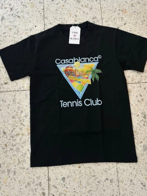 Casablanca Tennis Club - svart/ljusblå Tshirt - Snygg svart t-shirt från Casablanca med färgglatt tryck och texten 'Casablanca Tennis Club' på bröstet. Unik design som sällan syns. Storlek S. Pris kan diskuteras vid snabb affär.