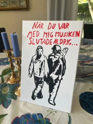 Håkan Hellström streetart canvas - Storlek 20x30cm Motiv, två personer som går bredvid varandra med texten ”När du var med mig musiken slutade aldrig…” i röd färg Målat på canvas duk med inbyggdkilram med akrylfärger, för hand. Motivet och citatet är taget rakt ifrån Håkan Hellström streetart  Hör av er ifall ni har frågor //Adam