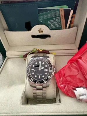 Rolle klocka silver  - Snygg Rolle klocka med svart urtavla och svart vridring. Klockan har en robust länk i silverfärgat stål och tydliga vita markeringar. Klassisk design med datumfönster och extra GMT-visare. Perfekt för dig som gillar exklusiva accessoarer.