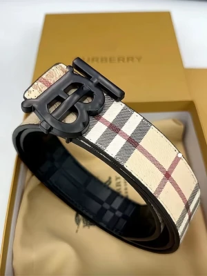 Burberry rutigt bälte med BB-spänne - Snyggt bälte från Burberry med klassiskt rutigt mönster i beige, svart och rött. Bältet har ett stort BB-spänne i svart metall och är gjort i skinn. Perfekt för att lyfta vilken outfit som helst.