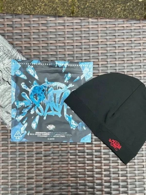 Y2K Central Cee Beanie - SynaWorld Syna Skull hat i röd. Sälj i nyskick.