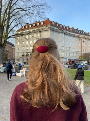 Vinröd hårklämma - Säljer en ovalformad hårklämma i vinröd sammet. Klämman har en stilren och enkel design som ger en snygg touch till din frisyr. Perfekt för att hålla halva håret uppe och passar till många olika looks.